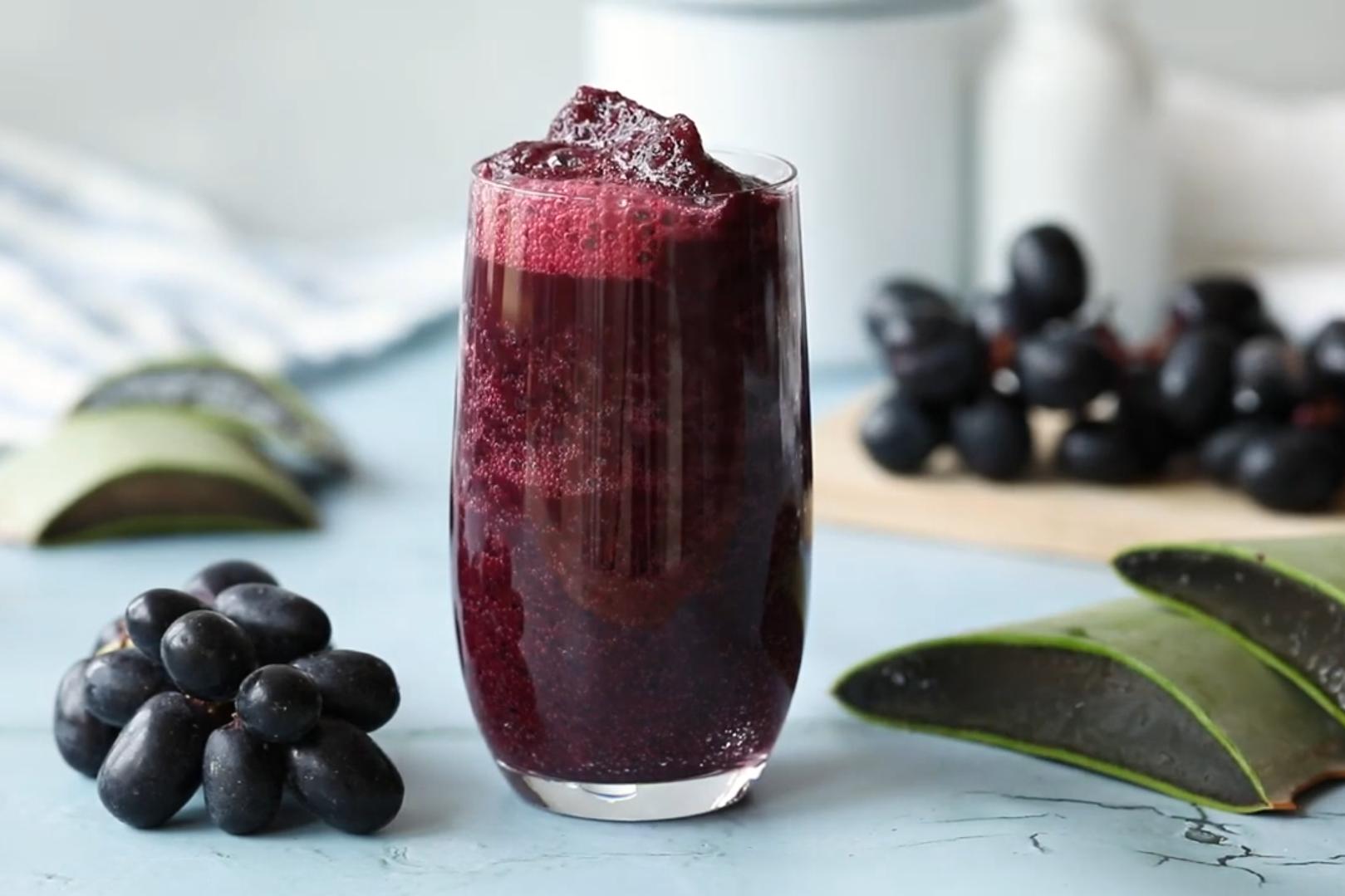 Purple grape aloe vera drink served with fresh grapes and aloe vera cubes.